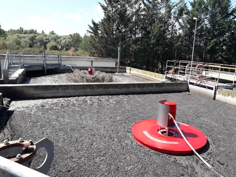 Red SCM AGV floating surface aerator on a round float in a concrete treatment basin